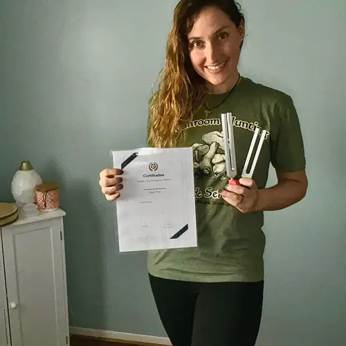 Morgan Bowers LMT owner of Heavenly Hands Massage LLC holding her certificate and tunning forks 